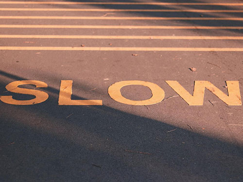 The word "slow" painted on pavement in yellow icon